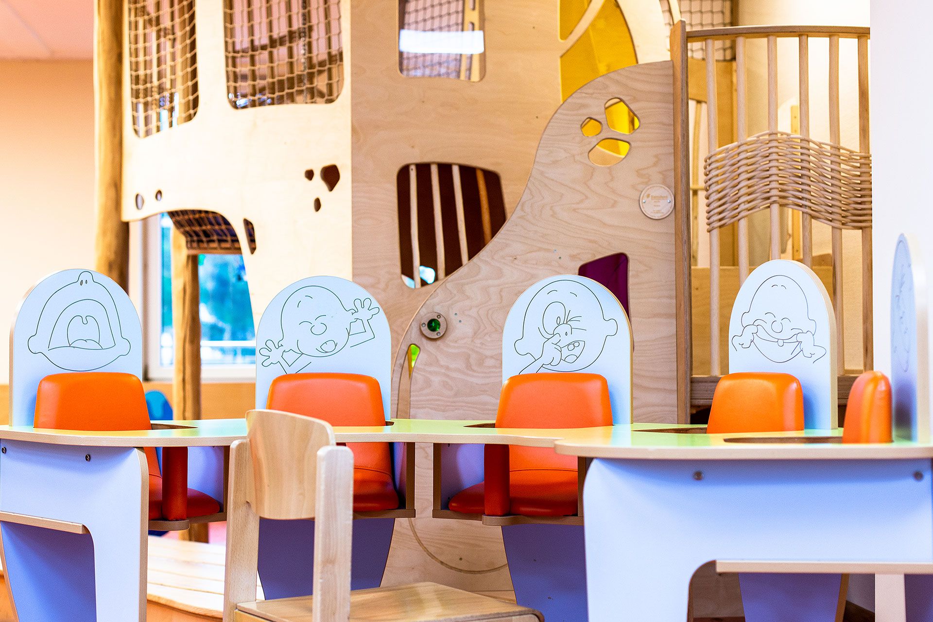 Four baby seats with funny caricatures making faces, a climbing frame in the background.